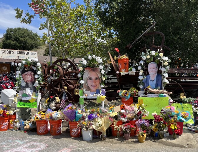A close-up look at the makeshift memorial outside Cook's Corner, site of a mass shooting that killed three: Home Depot buckets are overflowing with bouquets of flowers. There are flags, signs, notes and three large photos of the victims who died. 
