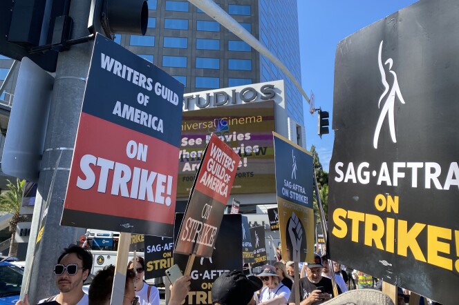 Hollywood strikers hold signs that say: "Writers Guild of America on Strike!" and "SAG-AFTRA on Strike!"
