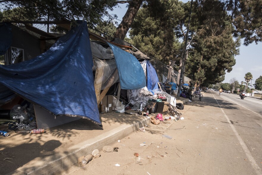 Tarps cover makeshift housing in Venice with litter in the dusty road
