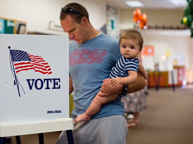 Jeff Thompson holds his 8-month-old son, Tyler, while voting in the Los Angeles County primary election at Canyon Springs School's library on Tuesday evening, June 3 in Santa Clarita.