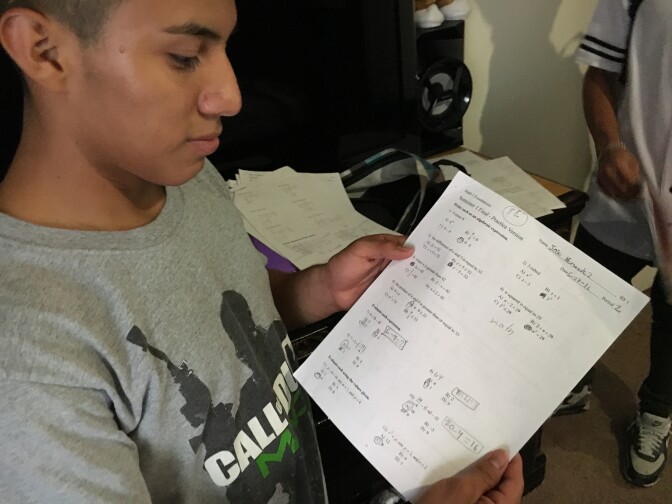 Luis González, 16, shows off his latest geometry homework in his bedroom at his family's home in La Quinta, California. He's adjusting to a new life in L.A. after being granted asylum in March, 2016.
