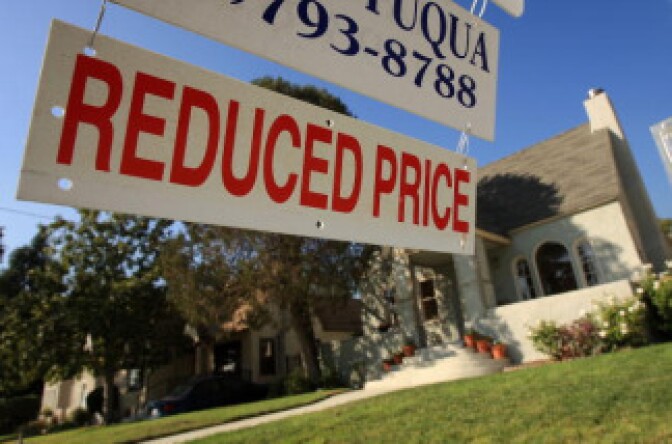 A realtor sign advertises that the price of a house has been reduced