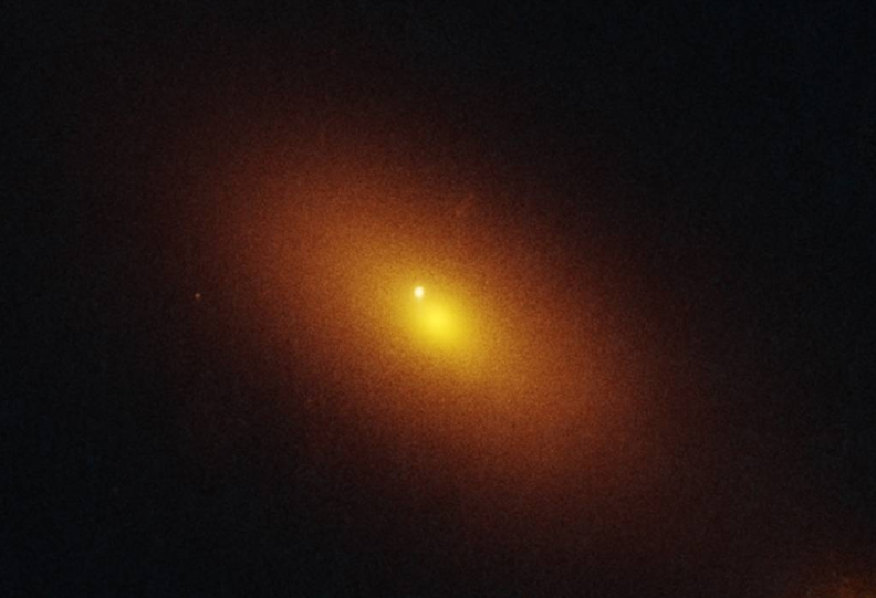 An orange glowing light radiates in deep space. The image quality is a little grainy.