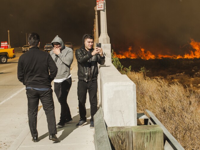 People take photos on their cell phones at the edge of the Creek Fire in Lakeview Terrace on Dec. 5, 2017.