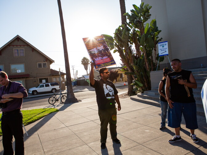 An activist holds a sign outside of Anaheim High School on August 8, 2012 during a special City Council meeting.
