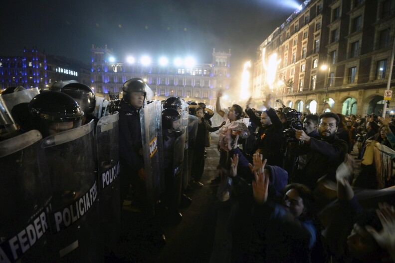 Members of Federal Police (L) confront protesters (R) outside Mexico's National Palace on Zocalo square in Mexico City, on November 20, 2014, over the safe return of 43 students who went missing in southern Mexico after an attack by gang-linked police last September 26. Protesters angry at the presumed massacre of 43 students clashed with police after a massive march demanding President Enrique Pena Nieto's resignation. AFP PHOTO/Alfredo ESTRELLA (Photo credit should read ALFREDO ESTRELLA/AFP/Getty Images)