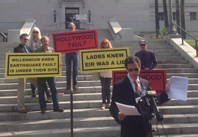 Attorney Robert Silverstein (holding papers) details e-mails from city officials indicating that they were concerned about an earthquake fault in Hollywood. Residents against the Hollywood Millennium project hold signs behind him on the steps of LA City Hall. 