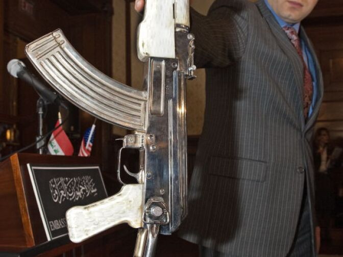 An official of the Iraqi Embassy in Washington, DC, holds a chrome-plated AK-47 with pearl hand grips and receiver that carries a photo on the receiver of Saddam Hussein near the rear sights,on February 25, 2010, during a press conference announcing the return to Iraq of six more cultural artifacts to the people of Iraq. 