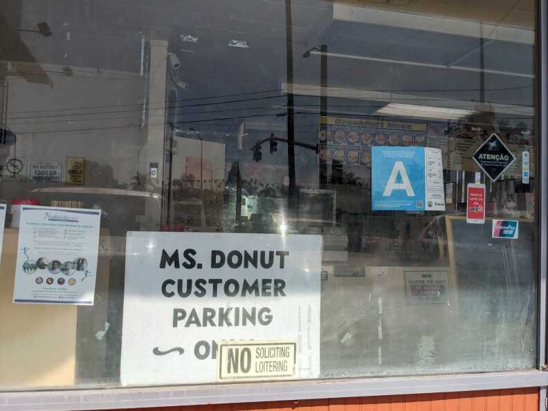A sign behind a storefront window that says, "Ms. Donut Customer Parking Only"