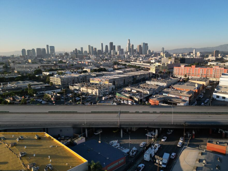 An empty stretch of elevated freeway. The Los Angeles city skyline rises in the background.