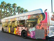 The exterior of a Metro bus covered with a colorful collage of portraits in different art styles.
