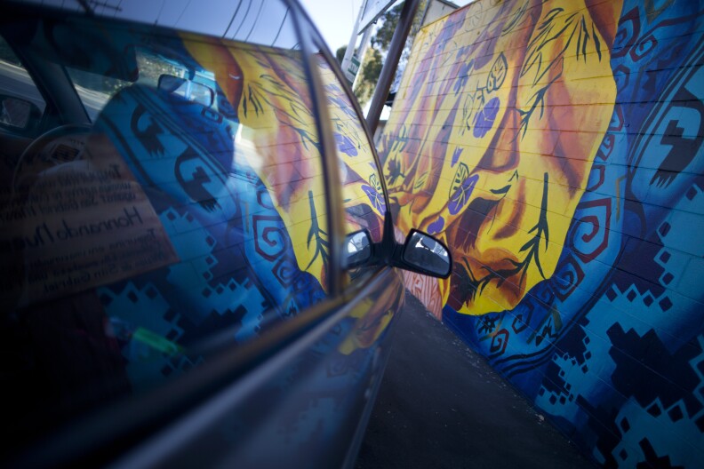 A car window reflects on of the pieces on Mural Mile along Van Nuys Boulevard in Pacoima.