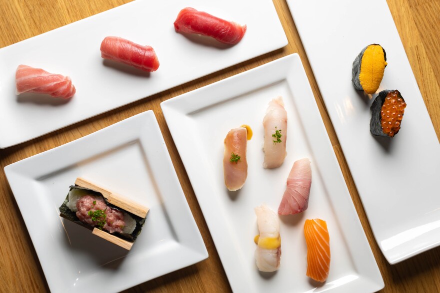 An overhead view of various white ceramic plates, both square and rectangular, each containing different types of sushi.