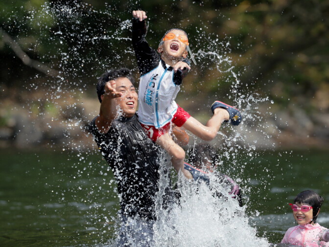 Family members play in the river at Shimanto city in Kochi prefecture on August 14, 2013. 