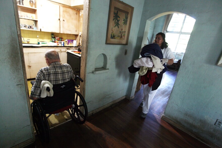 MIAMI - DECEMBER 14:  United HomeCare Services home health aide Wendys Cerrato carries bedding to the washing machine as she helps Robert Granville in his home on December 14, 2009 in Miami, Florida. The U.S. Senate continues to debate the need for the Community Living Assistance Services and Supports (CLASS) Act in the health care reform bill, which would provide a government-sponsored basic cash benefit to those needing long-term care services at home, in assisted living, or in a nursing facility. Without the help of United HomeCare Services Robert would be unable to continue to live on his own since he has limited mobility.  (Photo by Joe Raedle/Getty Images) *** Local Caption *** Robert Granville;Wendys Cerrato