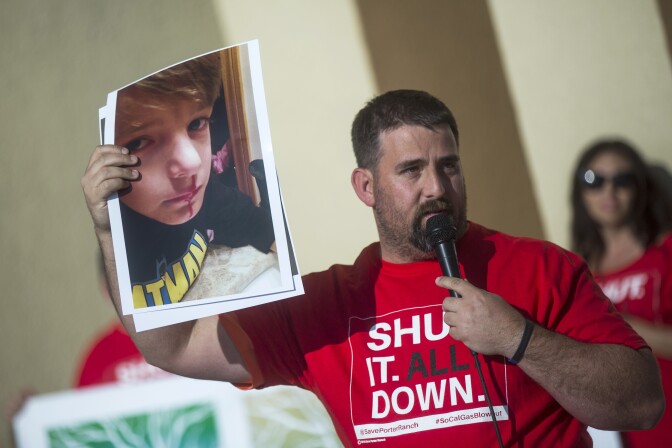 Andrew Krowne holds up a photo of his six-year-old son's bloody nose before a public health meeting at Porter Ranch Community School on Thursday evening, May 19, 2016 following a fall 2015 gas leak that led many residents to leave their homes. The family has been relocated for 119 days in a hotel.