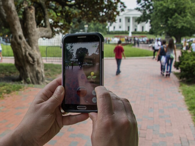 A woman holds up her cell phone as she plays the Pokemon Go game in Lafayette Park in front of the White House in Washington, D.C., July 12, 2016.