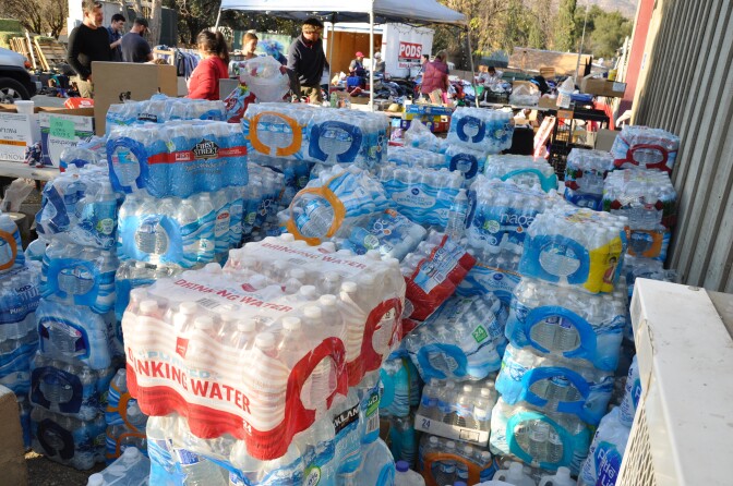 Shoulder-high stacks of bottled water sit outside the Stagecoach Station convenience store in Upper Ojai. The store has become a community hub and host to an ad-hoc relief station neighbors established in the wake of the Thomas Fire.