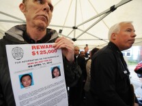 Los Angeles Police Department spokesman Richard French holds a poster offering a USD $125,000 reward for information leading to an arrest in the murder of Ming Qu (L) and Ying Wu (R), two University of Southern California (USC) students from China, during a news conference April 13, 2012 in the Los Angeles street where the murders occured two days ago.  