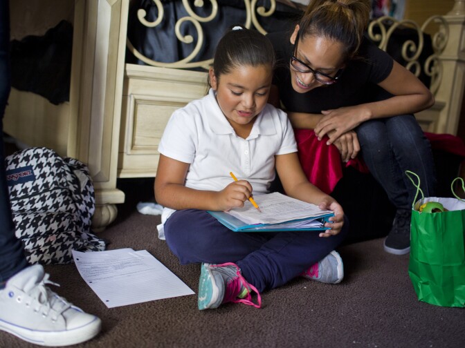 Raymond Zambrano's sisters Ciara Chavez, 8, left, and Ira Flores, 24, work on Chavez's homework in Zambrano's Panorama City home on April 27, 2015.