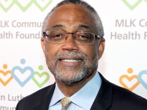 A light-skinned Black man with glasses, a short-cropped salt-and-pepper beard, and short-cropped salt-and-pepper hair, smiles at the camera.