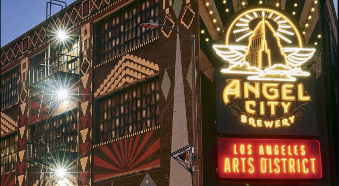 A neon-soaked corner of the Arts District, where Angel City Brewery’s glowing sign beams like a halo over a kaleidoscope of painted brickwork and sunbursts