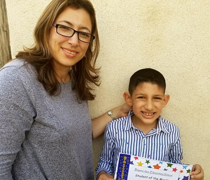 A woman, Tania Rivera, poses for a photograph next to her 11-year-old child, Luis, who is holding a certificate.