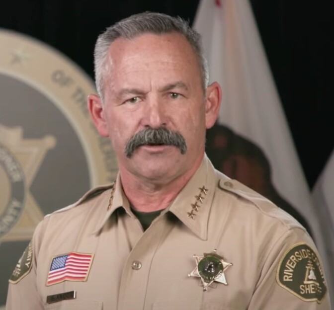 Riverside County Sheriff Chad Bianco poses for a portrait with an American flag in the background.