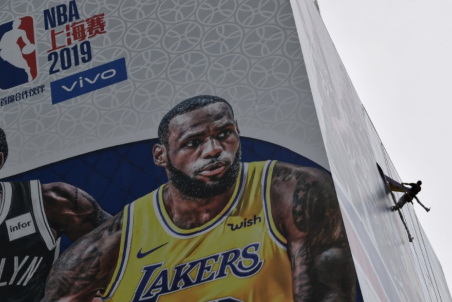 A worker removes a promotional banner from a building for the NBA October 10 preseason game in China between the Brooklyn Nets and the Los Angeles Lakers in Shanghai.