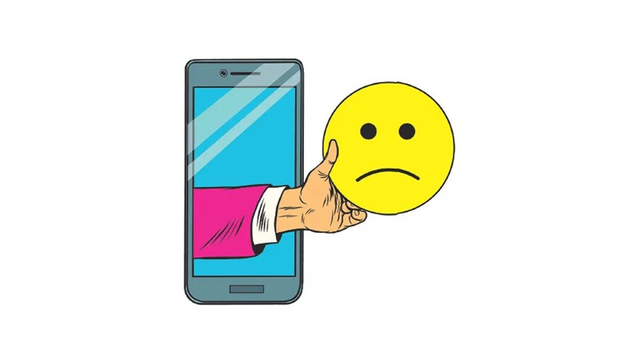 An illustration of a white person's hand reaching out of the screen of a smartphone and holding a round, yellow sad face emoji. 