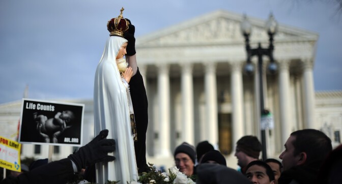 A marcher places a crown atop a statue of the Virgin Mary as she is carriedinfront of the US Supreme Court during the March for Life on January 24, 2011 on Capitol Hill in Washington, DC.The march marks the 38th anniversary of Roe v. Wade (officially Jan. 22), a landmark Supreme Court decision that legalized abortion.     AFP PHOTO / Tim Sloan (Photo credit should read TIM SLOAN/AFP/Getty Images)