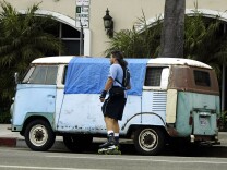  A skater passes a van where a homeless person is sleeping July 13, 2004 in Venice, California. 
