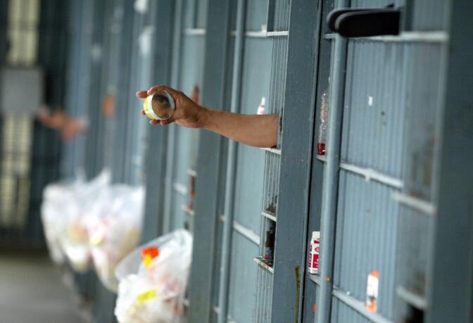 An immate uses a mirror to look outside his cell at the Los Angeles Men's Central Jail in downtown Los Angeles, 19 May 2004. 