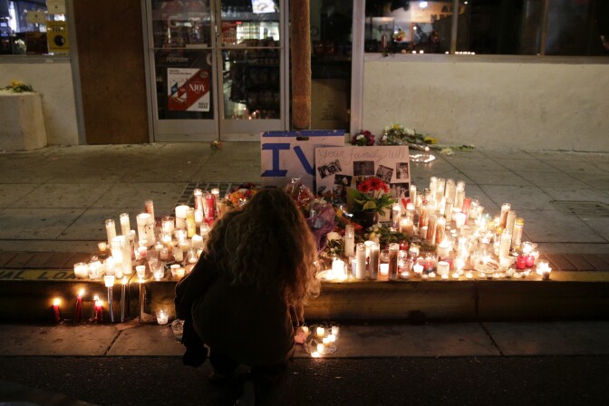 A woman places a candle in front of IV Deli Mart, where par of Friday night's mass shooting took place by a drive-by shooter, on Saturday, May 24, 2014, in the beach community of Isla Vista, Calif. Sheriff's officials say Elliot Rodger, 22, went on a rampage near the University of California, Santa Barbara, stabbing three people to death at his apartment before shooting and killing three more in a crime spree through a nearby neighborhood. (AP Photo/Jae C. Hong)