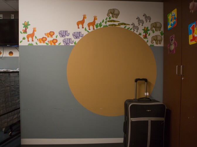 An unused piece of luggage is left behind in a room used for children who have been taken into protective custody.