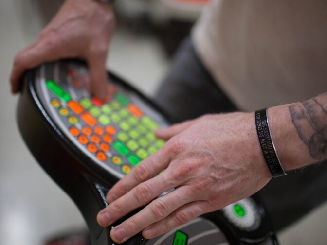 Joe McGraw, an Army veteran with eight years of service, inputs names into the bowling scoreboard. He wears a bracelet in memory of a fallen comrade.