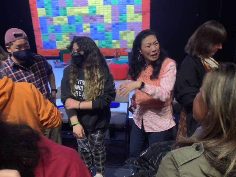 Audience members surround performer Kristina Wong, wearing a pink sweater vest after her show.