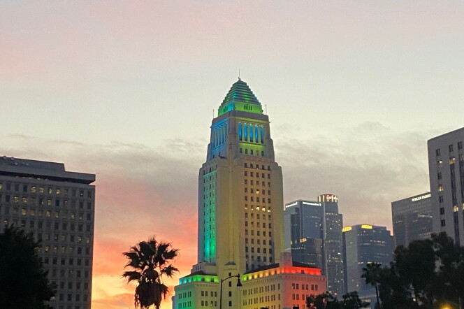 City Hall is lit up at dusk next to the 101 freeway.