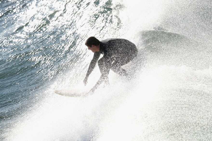 Surfer in a black wetsuit riding a cresting wave.