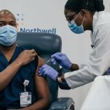 NEW YORK, NY - DECEMBER 14: Lenox Hill Hospital Chair of Emergency Medicine Yves Duroseau receives the COVID-19 vaccine at Long Island Jewish Medical Center on December 14, 2020 in New Hyde Park on Long Island, New York. The first vaccination was administered to a frontline healthcare worker Monday, with Governor Andrew Cuomo attending the event remotely. (Photo by Scott Heins/Getty Images)