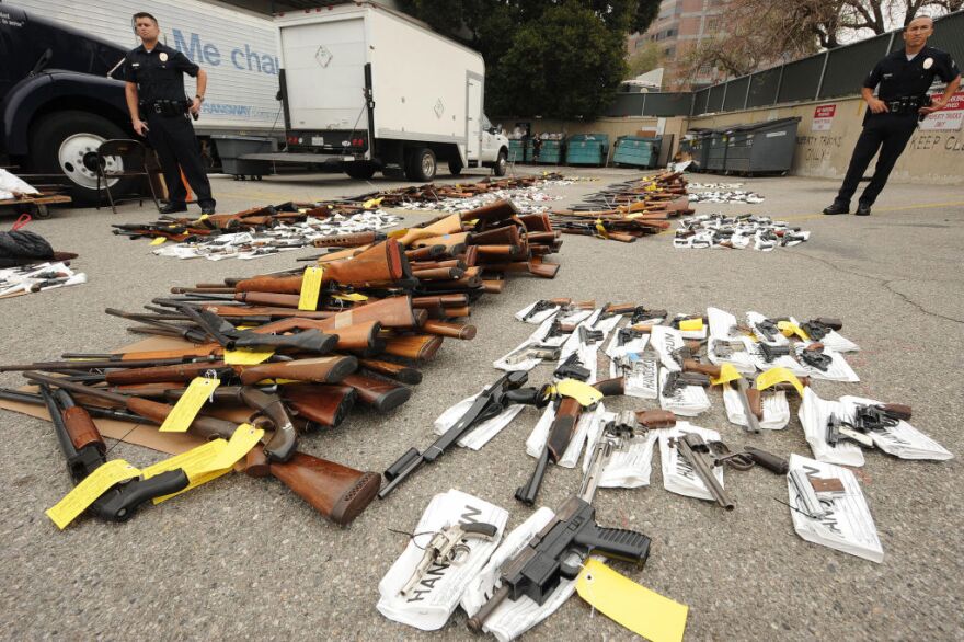 Police guard some of the more than 1,600 firearms which were voluntarily surrendered to police custody over a five-hour period last Saturday are on display at a press conference at police headquarters in Los Angeles, California on May 11, 2009.  More than 1,600 firearms were voluntarily surrendered to police custody over a five-hour period May 9, 2009 in the one-day gun buyback program in which citizens who turned in a handgun, shotgun or rifle received a USD100 voucher for a local supermarket while people who turned in higher caliber assault weapons such as a AK-47, Uzi or AR-15 received a voucher worth USD200.  The gun buyback program is a component of Mayor Antonio Villaraigosa's 2009 gang plan to reduce gun violence.  At right is city councilmember Jack Weiss and second from left is the mayor's anti-gang czar Rev. Jeff Carr.  