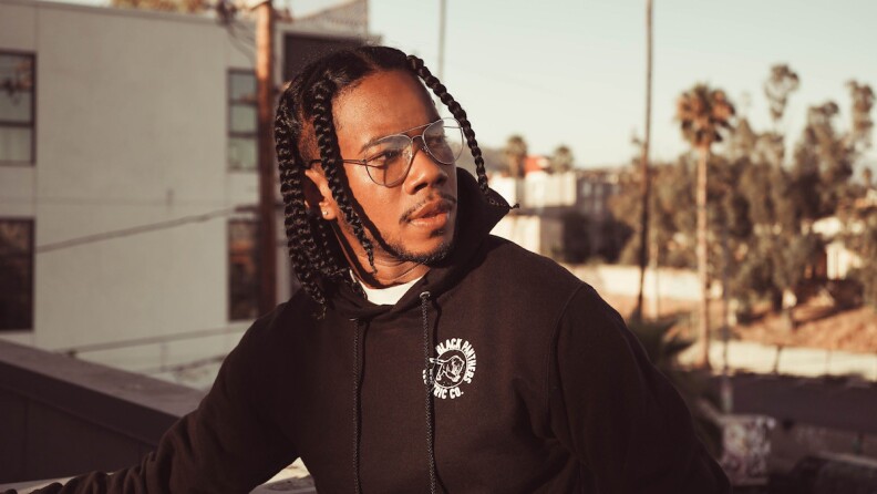 Ray Kirk stands on a rooftop in a black sweatshirt looking to his left.