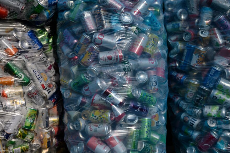 A close-up of multiple large transparent plastic bags of empty beverage cans.