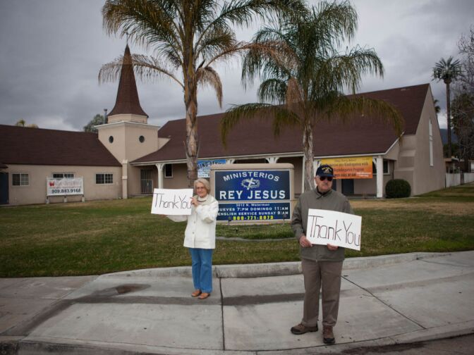 Judy and Paul Grantham of Yucaipa hold signs in appreciation of Det. Jeremiah MacKay in San Bernardino.