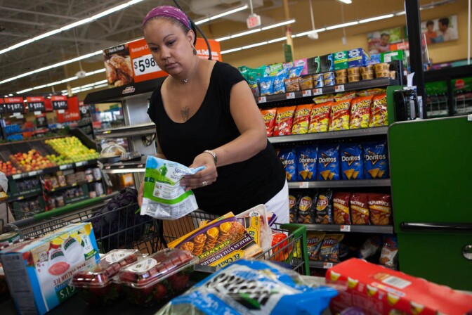 Sandi Vaughn unloads her cart, including two bins of strawberries, on to the checkout stand at a Walmart Neighborhood Market in Santa Clarita, Calif.