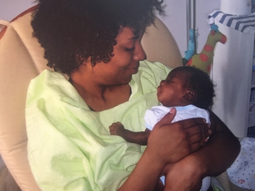 A woman with dark-tone skin hold a newborn with dark-tone skin