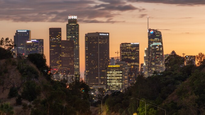 Tall skyscrapers appear against a sky at dusk.