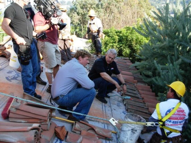 The cast and crew of "This Old House" tapes on a rooftop in Silverlake. That's host Kevin O'Connor in the blue shirt, learning about attaching clay roof tiles from the roofing contractor.