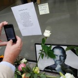 A mourner takes a picture of flowers placed outside of the Apple Store in remembrance of Steve Jobs, founder and former CEO of Apple Inc.