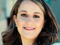 Imelda Padilla, a light-skinned Latina, smiles at the camera. She has brown eyes, and dark hair with a few blond streaks in it. 